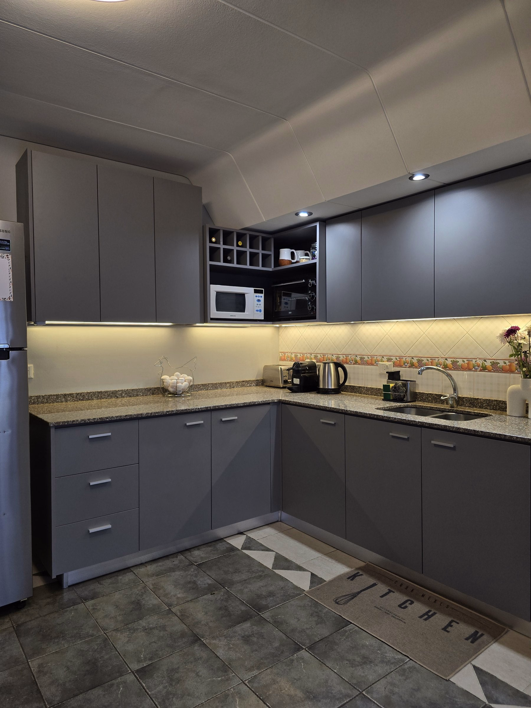 Cocina terminada en Benito Juárez, Villa Devoto: muebles grises, mesada de granito y luz bajo alacena